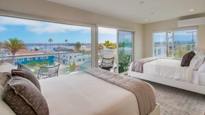 Une chambre d’hôtel moderne avec un grand lit, un plus petit lit et un balcon offrant une vue sur la ville.