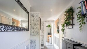 A hallway with a marble wall, a black console, and a mirror.