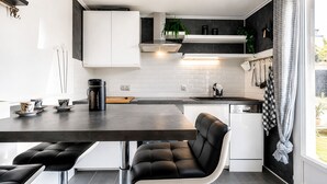 A modern kitchen with a dark countertop, white cabinets, and a black chair.