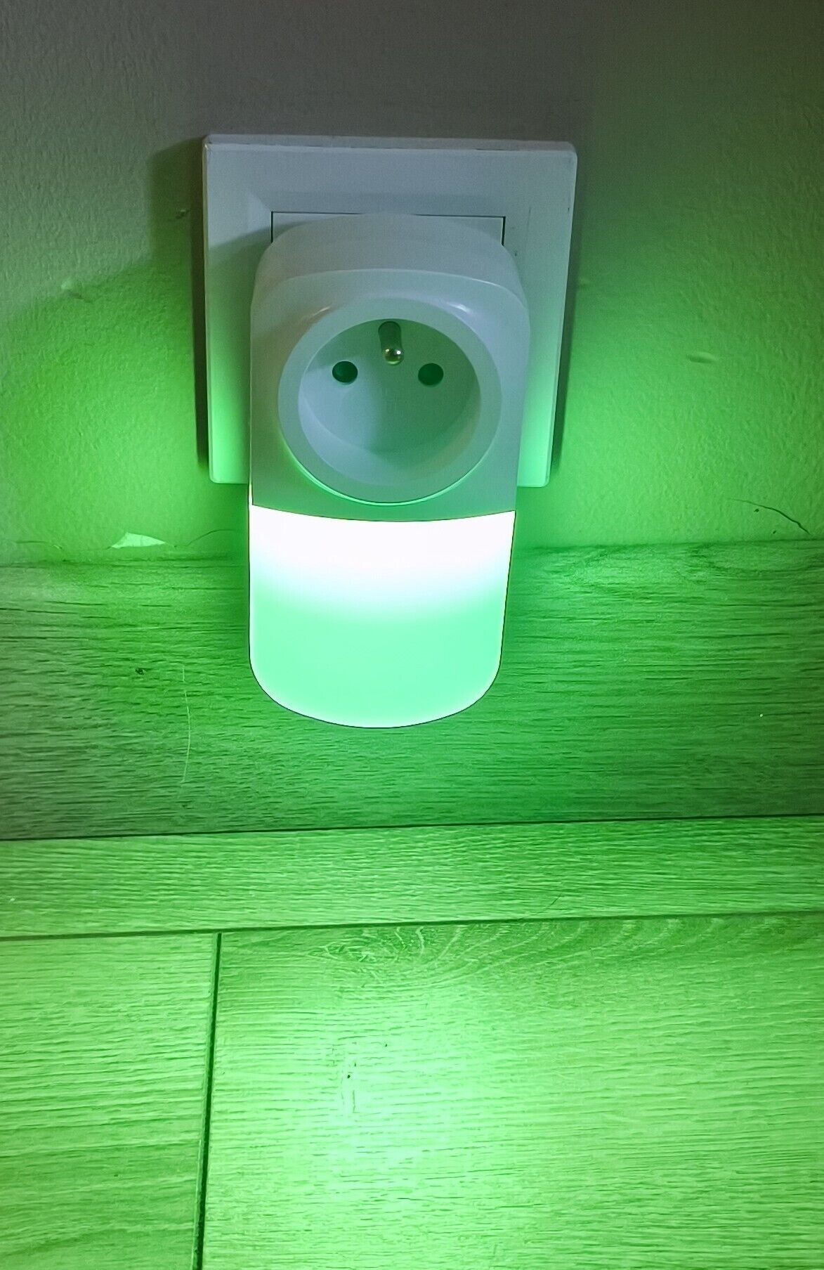 Una presa elettrica a muro con una luce verde.