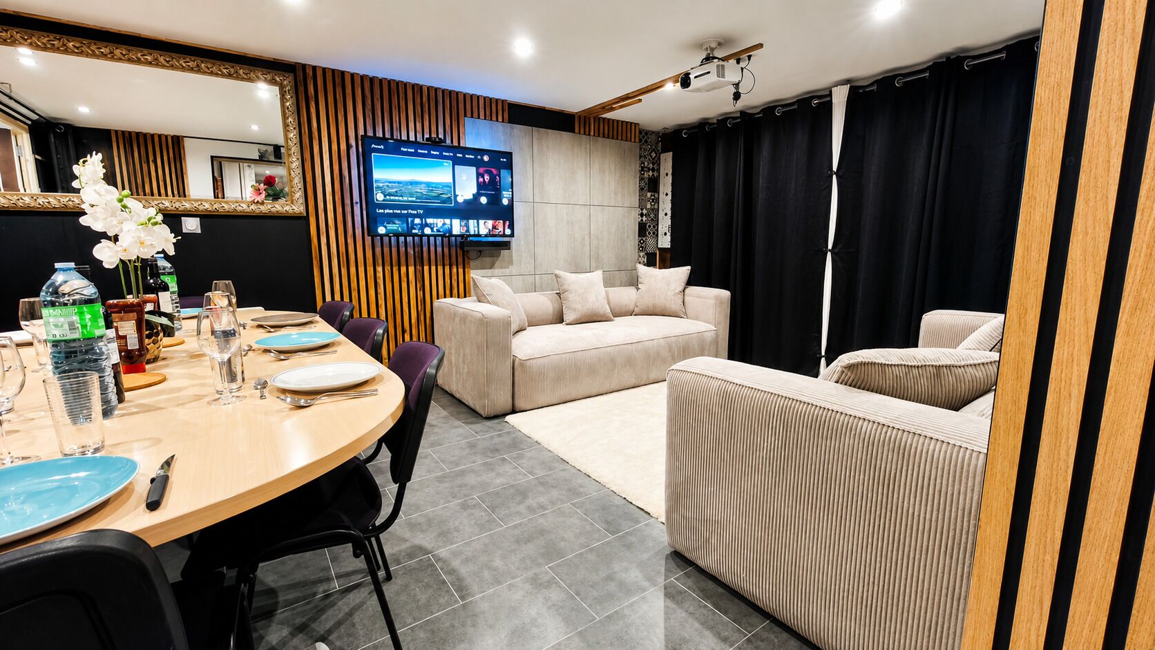 Un salon moderne avec un téléviseur, un canapé et un coin repas.
