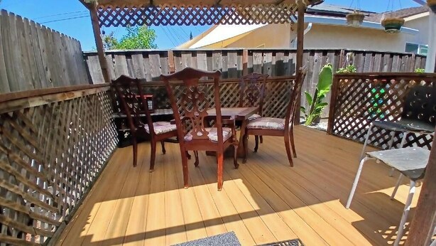 A wooden deck with a wooden table and chairs, surrounded by a wooden fence and lattice panels. - Private Room with Ensuite Bath - Separate Entrance and Exit! (San Jose)