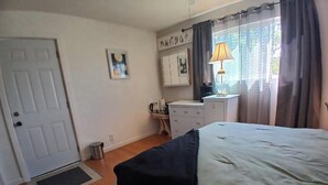 A bedroom with a bed, a bedside table with a lamp, a wardrobe, and a door. - Private Room with Ensuite Bath - Separate Entrance and Exit! (San Jose)