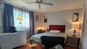 A bedroom with a bed, bedside tables, a desk, a chair, a ceiling fan, and a window with curtains. - Private Room with Ensuite Bath - Separate Entrance and Exit! (San Jose)