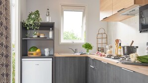 Cocina compacta con refrigerador integrado, muebles oscuros, una ventana y una pequeña isla con utensilios de cocina.