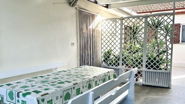 A room with a white bench, a table with a green and white patterned tablecloth, and a white lattice partition. - RM10 - Senigallia, two-room apartment facing the sea (Senigallia)