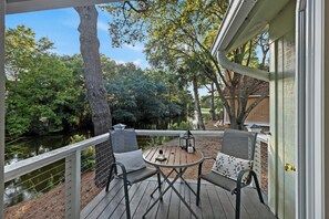 A wooden deck with a table and chairs, overlooking a pond and trees. - Great FAMILY home in Wild Dunes, Pond View, Modern, Minutes to Beach, Rent the Golf Cart! (Isle Of Palms)
