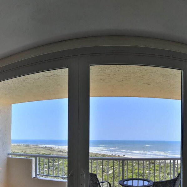 A balcony with a view of the ocean and a table with chairs. - Sun, Sea & Salty Breeze | Inlet #1103 (New Smyrna Beach)