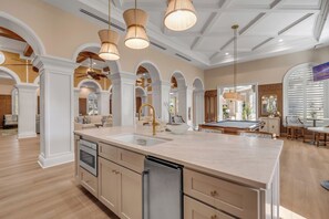 A spacious kitchen with a large island, modern appliances, and a dining area with a pool table. - Sun, Sea & Salty Breeze | Inlet #1103 (New Smyrna Beach)