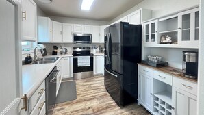 Une cuisine moderne avec des meubles blancs, des appareils en acier inoxydable et un plancher en bois.