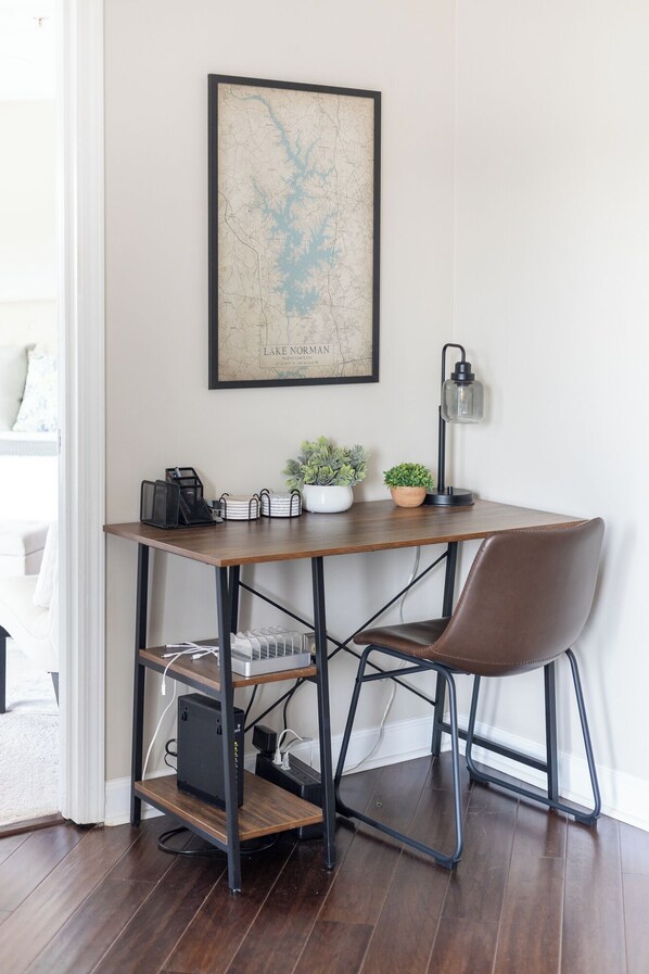 Un espacio de trabajo con escritorio, silla, computadora y un mapa enmarcado del Lago Norman.