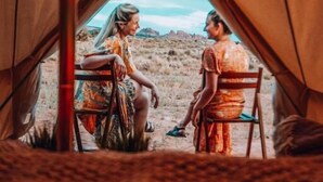 A tent with two people seated inside, facing each other. - Yellowstone Glamping (Island Park)