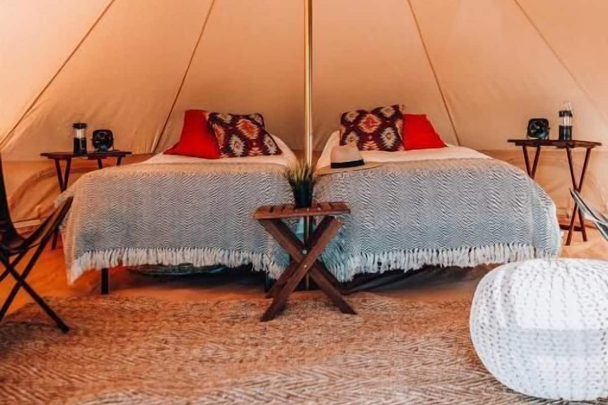 Ein gemütliches Zelt mit Bett, Kissen, einem kleinen Tisch und einem Teppich.