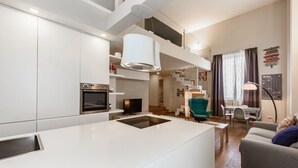 Une cuisine moderne dotée d’un îlot central, d’un four encastré et d’un coin repas avec une table et des chaises.