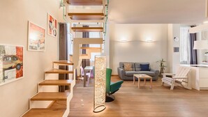 Un salon moderne avec un escalier en bois, un canapé, une table basse et un fauteuil.