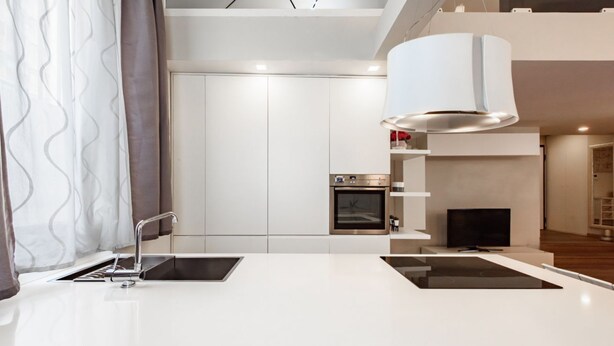Une cuisine moderne dotée d’un îlot central, d’un four encastré et d’un téléviseur.