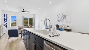 Une cuisine moderne dotée d’un grand îlot central, d’un ventilateur de plafond et d’une carte accrochée au mur.