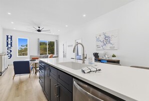 Une cuisine moderne dotée d’un grand îlot central, d’un ventilateur de plafond et d’une carte accrochée au mur.