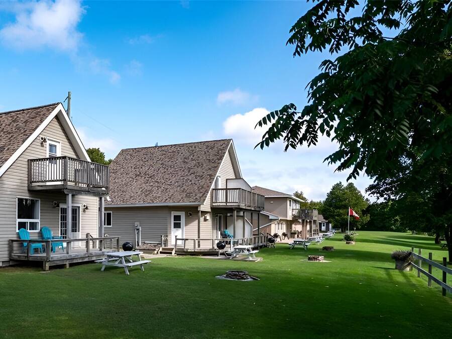 A row of single-story houses with attached porches, a well-maintained lawn, and outdoor seating areas.