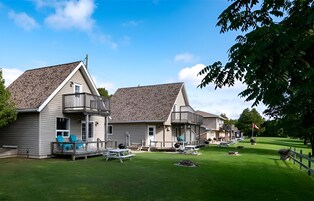 Una hilera de casas de un piso con porches incorporados, un césped bien cuidado y zonas de estar al aire libre.
