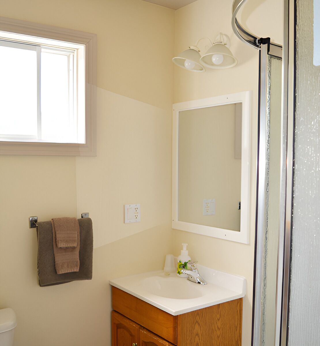 A bathroom with a window, a sink, a mirror, and a towel rack.