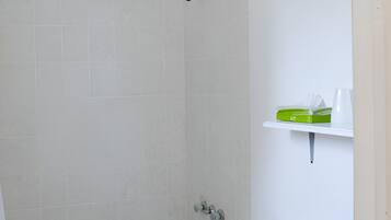 A bathroom with a bathtub, toilet, and a shelf with toiletries.