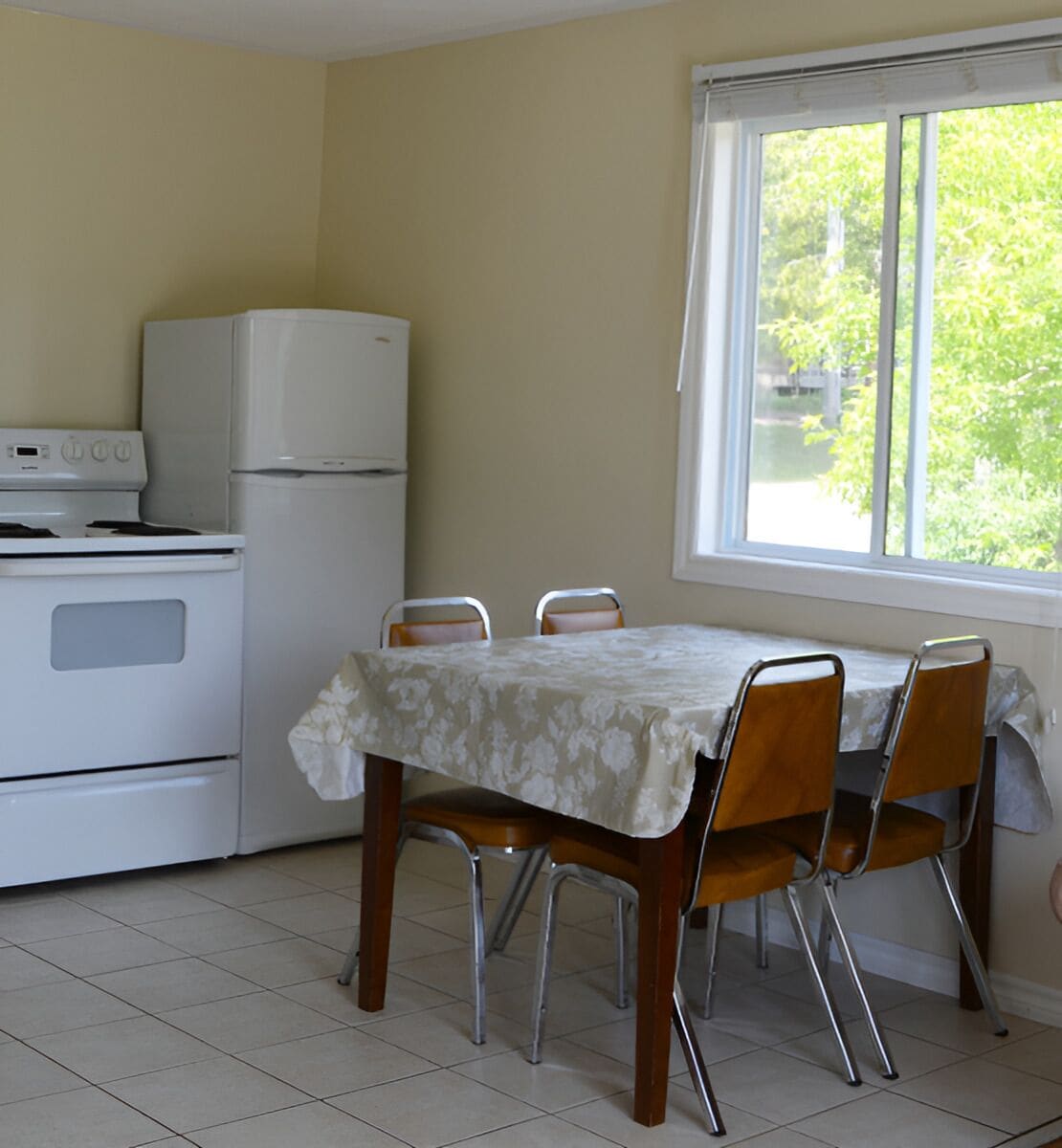 Une cuisine équipée d’une table et de chaises, d’un réfrigérateur et d’un four.