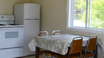 A kitchen with a dining table and chairs, a refrigerator, and an oven.