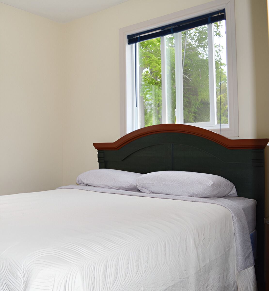 A bed with a wooden headboard in a room with a window.