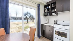 Une cuisine moderne dotée d’une grande fenêtre, d’une table à manger et offrant une vue sur un lac.