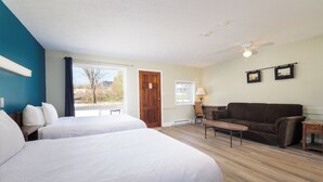 Une chambre d’hôtel avec deux lits, un canapé, une table et un ventilateur de plafond.