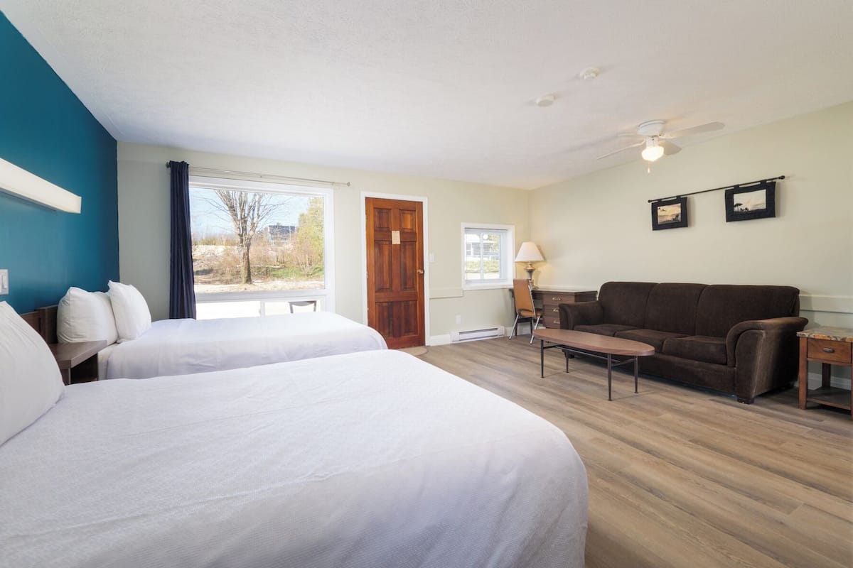 Habitación de hotel con dos camas, un sofá, una mesa y un ventilador de techo.