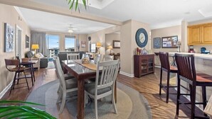 A spacious living room with a dining area, kitchen, and a view of the outdoors.