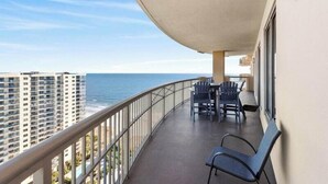 Un balcon avec vue sur l’océan, une table avec des chaises et une rambarde.