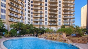 Une piscine dont la profondeur maximale est indiquée à 1,5 mètre, entourée d’une terrasse en briques et agrémentée d’un élément décoratif en roche.