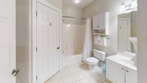 A bathroom with a toilet, bathtub, shower curtain, and a mirror above the sink. - Cozy Golf Villa | Pool View Paradise | Relax | Magnolia North 4872-203 (Myrtle Beach)