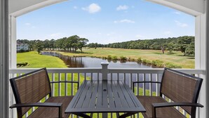 Ein Balkon mit Blick auf einen Golfplatz, einen Teich und ein Gebäude im Hintergrund.