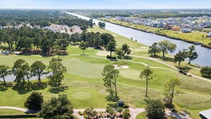Ein Golfplatz mit Fluss, Häusern und Bäumen.