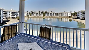 A balcony with a view of a calm lake, surrounded by multi-story buildings. - Myrtlewood Villa Close to Beach & Dining | Magnolia Pointe Luster Leaf 4837-201 (Myrtle Beach)