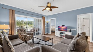 A spacious living room with a ceiling fan, a sofa set, a coffee table, and a television. - Pool View Bliss | Relax & Unwind | Myrtle Beach Awaits | Magnolia North 4827-202 (Myrtle Beach)