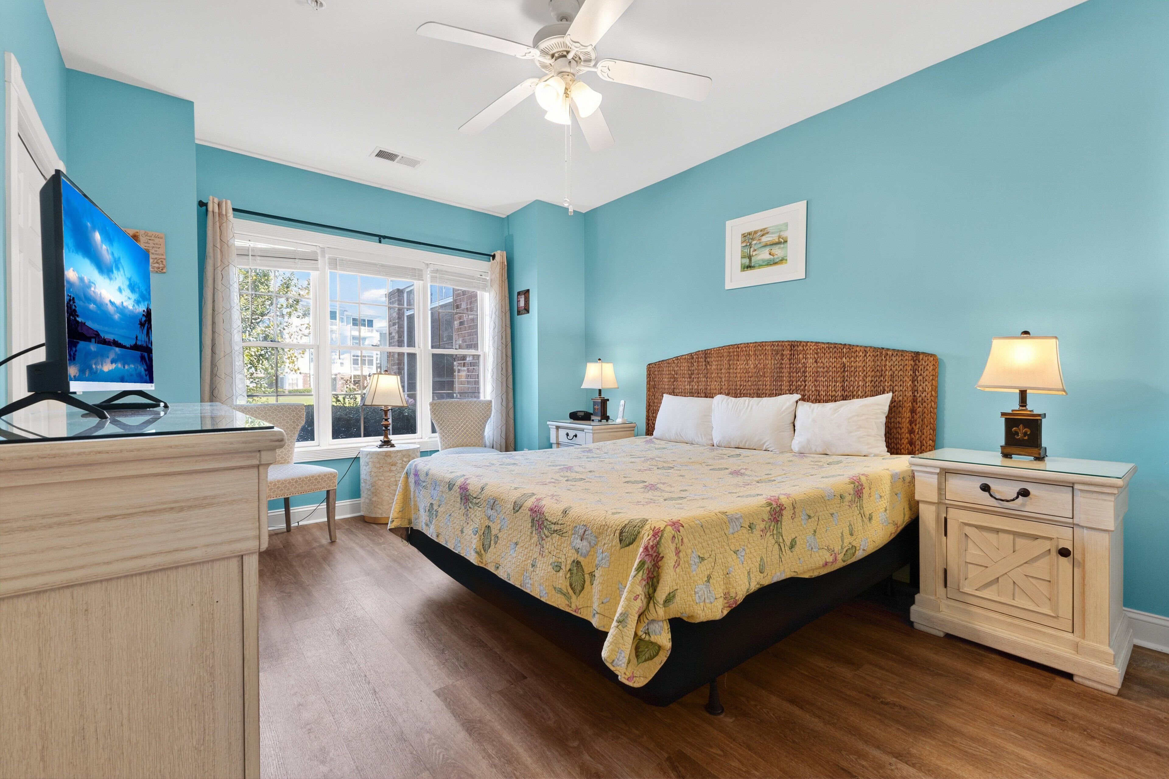 A bedroom with a bed, nightstands, a desk, and a window.