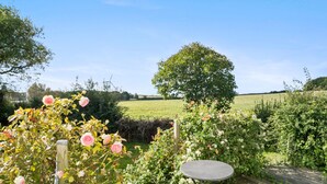 A garden with a wooden deck, a round table, and blooming roses.