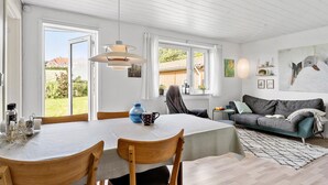 A bright, open-plan living space with a dining area, a sofa, and artwork on the walls.