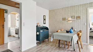 A modern dining area with a table set for two, a blue dresser, and a kitchen visible in the background.