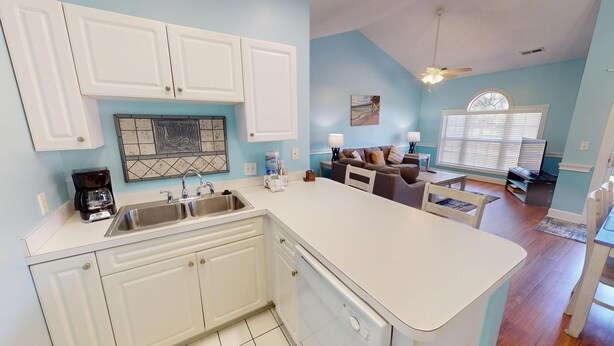 A modern kitchen with white cabinets, a double sink, and a coffee maker.