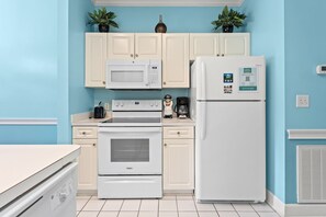 A kitchen with white cabinets, a microwave, a refrigerator, a stove, and a toaster. There are two potted plants on the cabinets. - Serene Garden Views | Beach & Golf Retreat | Magnolia Place 4627-302 (Myrtle Beach)