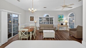 A spacious living room with a dining area, a sofa, and a ceiling fan. - Magnolia Place 4709-301 | Coastal feel | peaceful spot | walk to golf (Myrtle Beach)