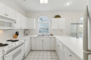 A modern kitchen with white cabinetry, a built-in microwave, a stove, and a sink. - Myrtlewood Villas| Golf & Garden Views Await You | Magnolia Place 4647-201 (Myrtle Beach)