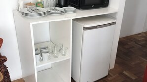 Een kleine keuken met een magnetron, koffiezetapparaat en opslagplanken.
