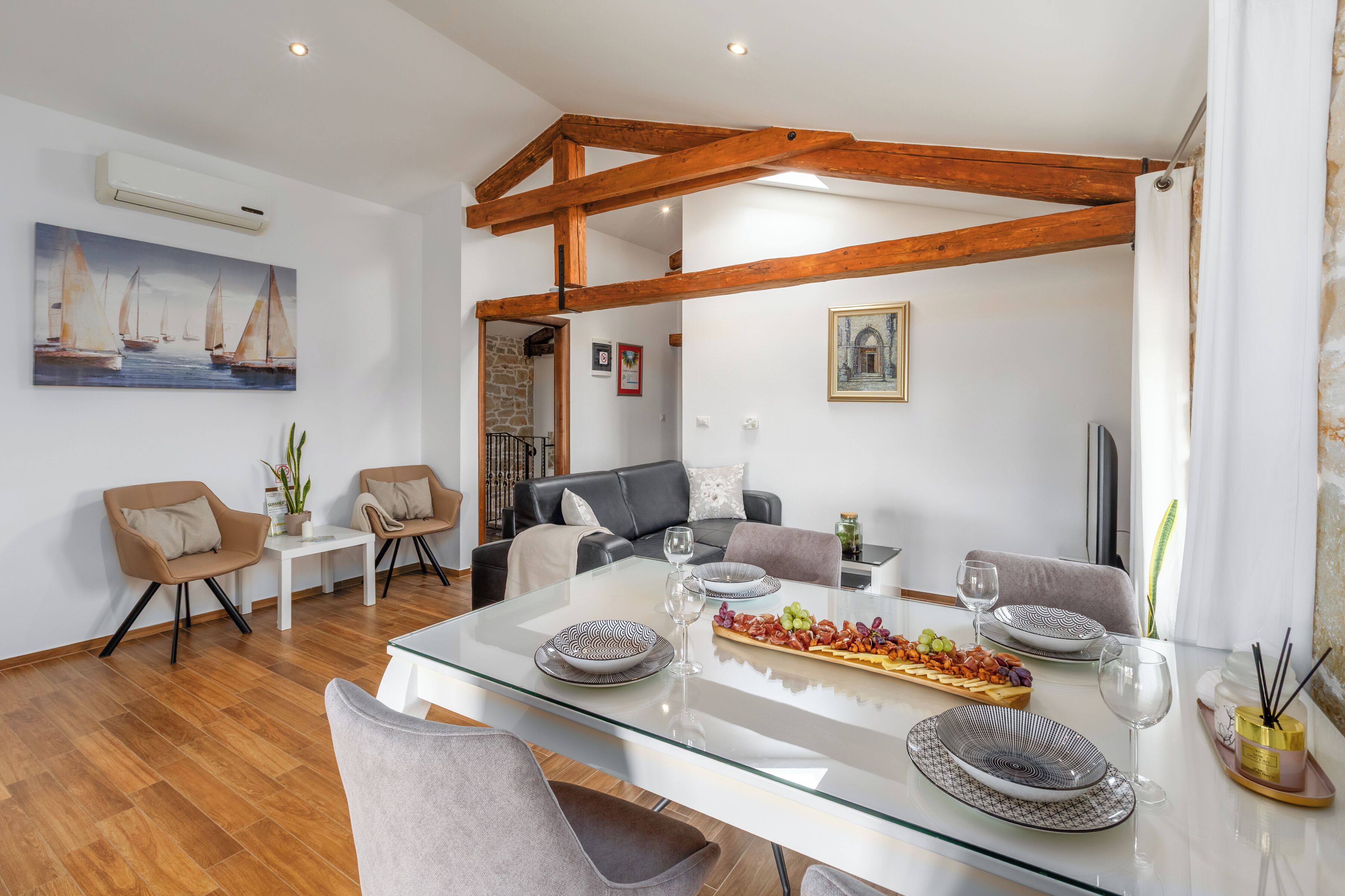 Un espace repas moderne avec une table en verre, des poutres en bois et différents types de sièges.